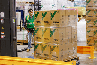 a man stands next to a boxes wrapped in stretch wrap on a pallet