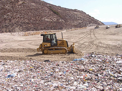 Figure 3 - Small dozer placing thin layer of daily cover soil on smooth trash surface.