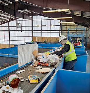 person in hard hat and work vest sorting material